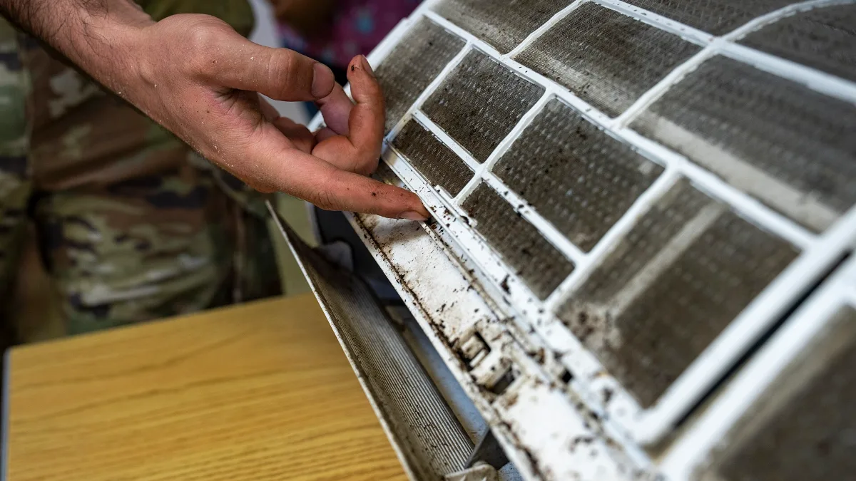 Técnico muestra el polvo acumulado en el filtro del split de aire acondicionado antes de limpiarlo