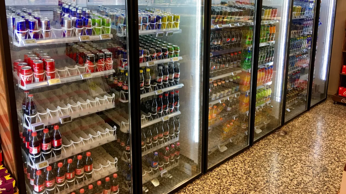 Neveras comerciales de puerta de vidrio con bebidas frías en un minisúper, cuyo condensador requiere limpieza